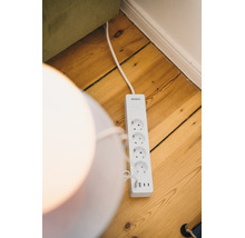 Osram Smart plus Steckdosenleiste mit vier Steckplätzen und drei USB-Anschlüssen auf Holzboden, Osram Logo.