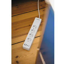 Smarte Mehrfachsteckdose von Osram mit vier Steckplätzen und vier USB-Anschlüssen auf einem Holzboden.