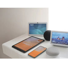 Verschiedene Smart Home Geräte wie Tablet, Smartphone, zwei Smart Displays und zwei Smart Speaker auf einer Ablage.