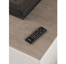 Osram Fernbedienung für smarte Beleuchtung auf einer Steinfläche neben einem modernen Kamin.