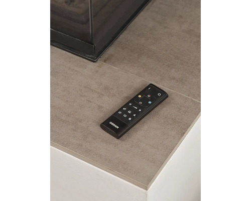 Osram Fernbedienung für smarte Beleuchtung auf einer Steinfläche neben einem modernen Kamin.