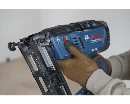 Bosch Professional Akku-Nagler GNH 18V-64-2 M wird von einer Person mit Arbeitshandschuhen bedient.