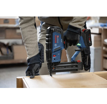 Eine Person benutzt einen Bosch Professional Akku-Nagler auf einem Werkstück aus Holz.