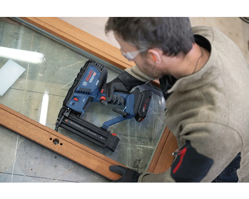 Handwerker verwendet einen Bosch Professional Akku-Nagler an einem Holzfensterrahmen.