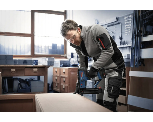 Handwerker nutzt einen Bosch Professional Akku-Nagler zum Bearbeiten von Holz in einer hellen Werkstatt.
