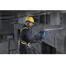 Ein Bauarbeiter mit Sicherheitsgurt und Helm benutzt ein Bosch Akku-Werkzeug an einer Metallstruktur auf einer Baustelle.
