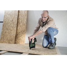 Ein Mann mit Schutzbrille befestigt eine OSB-Platte mit einem Akku-Tacker von Bosch auf einer Holzunterkonstruktion.