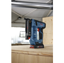 Bosch Professional Akku-Stiftnagler mit bürstenlosem Motor auf einer Holzplatte in einer hellen Werkstatt.