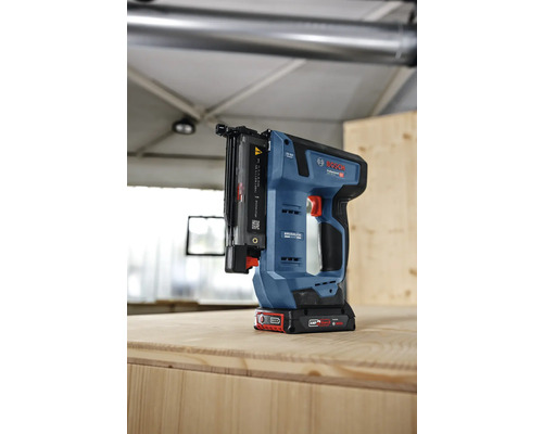 Bosch Professional Akku-Stiftnagler mit bürstenlosem Motor auf einer Holzplatte in einer hellen Werkstatt.