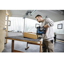 Handwerker montiert eine Holzschublade mit einem Akku-Tacker in einer hellen, organisierten Werkstatt.