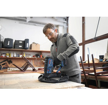 Handwerker nutzt Bosch Professional Akku-Tacker zur Polsterung eines Hockers in einer hellen Werkstatt.