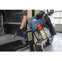 Eine Person verwendet einen Bosch Professional Akku-Staubsauger mit Schultergurt und Schlauch zur Reinigung von Sägespänen in einem Transporter.