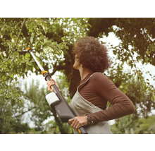 Frau benutzt eine Akku-Astschere im Garten, um Äste zu schneiden.