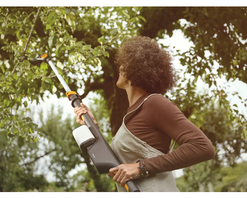 Frau benutzt eine Akku-Astschere im Garten, um Äste zu schneiden.