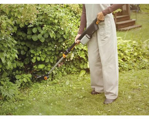 Person bedient eine Akku-Heckenschere im Garten.