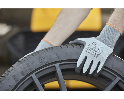 Eine Person mit Schutzhandschuhen hält einen schwarzen Reifen.