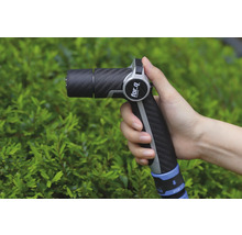 Eine Hand hält eine Gartenspritze der Marke For Q vor einem grünen Busch