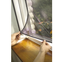 Person befestigt ein Insektenschutzgitter an einem Fenster.