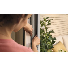 Frau befestigt ein Insektenschutzgitter an einem Fenster.