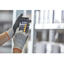 Eine Person mit Arbeitshandschuhen benutzt einen Taschenrechner auf einem Smartphone.