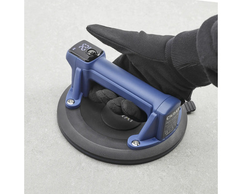 Carat digitaler Saugheber mit Digitalanzeige, Hand mit Arbeitshandschuh setzt den Vakuumheber auf eine Fliese auf.
