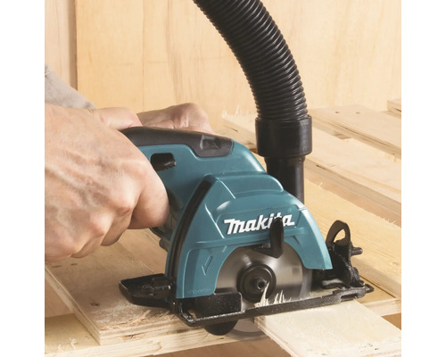 Makita Handkreissäge schneidet Holz mit angeschlossenem Staubsaugerschlauch.