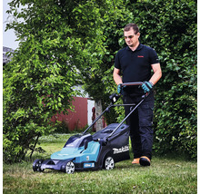 Ein Mann mäht den Rasen in einem Garten mit einem Makita Akku-Rasenmäher.