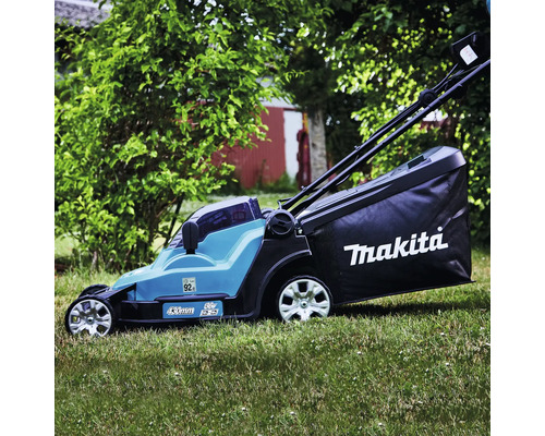 Makita Akku Rasenmäher mit 430 Millimeter Schnittbreite und Fangkorb im Einsatz auf einer Rasenfläche im Garten.