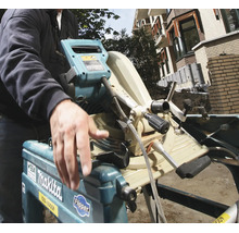 Eine Person bedient eine Makita Flipper Tisch- und Kappsäge im Außenbereich auf einer Baustelle.
