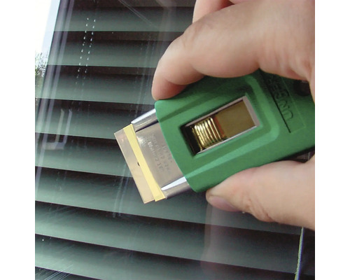 Eine Hand benutzt einen Glasschaber mit Klinge zur Fensterreinigung.