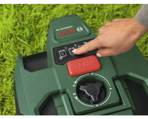 Nahaufnahme eines Bosch Mähroboters mit einer Hand, die das Bedienfeld berührt, mit rotem Stoppknopf und schwarzem Drehknopf zur Einstellung der Schnitthöhe.