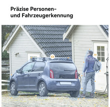 Ein Elektroauto lädt vor einem Haus mit einer Person im Hintergrund