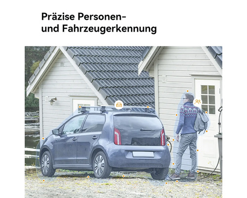 Ein Elektroauto lädt vor einem Haus mit einer Person im Hintergrund