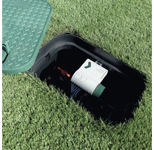 Geöffnete Ventilbox im Rasen mit Rain Pure Vision Bewässerungssteuerung und rotem Handventil.