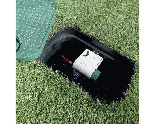 Geöffnete Ventilbox im Rasen mit Rain Pure Vision Bewässerungssteuerung und rotem Handventil.
