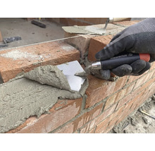 Maurer legt Ziegel mit einer Maurerkelle auf einer Baustelle