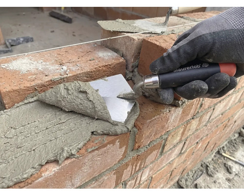 Maurer legt Ziegel mit einer Maurerkelle auf einer Baustelle