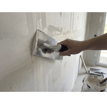 Handwerker glättet Wand mit Glättkelle und Putz