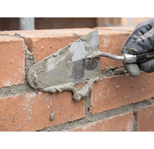 Maurer beim Verfugen einer Ziegelwand mit einer Maurerkelle