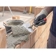 Maurer beim Verarbeiten von Mörtel und Ziegelsteinen für den Wandbau