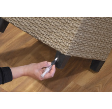 Eine Person repariert ein Rattanmöbelstück mit einem Reparaturstift.