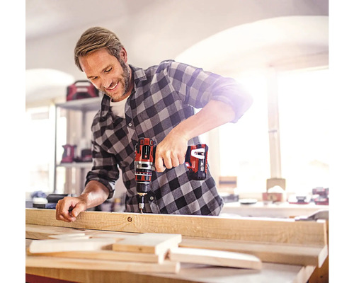 Ein Mann bohrt mit einem Akku-Bohrschrauber ein Holzbrett.