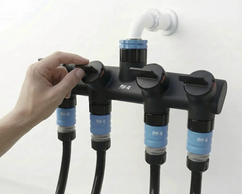 Gartenschlauchverteiler mit vier Anschlüssen und Hand, die einen der Hähne bedient