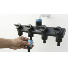 Wasserverteiler mit vier Ausgängen zur Gartenbewässerung wird an einen Gartenschlauch angeschlossen