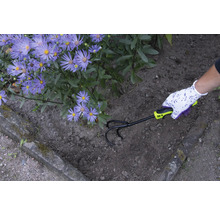 Gartenarbeiter lockert Erde mit einem Kultivator neben lila Blumen auf.