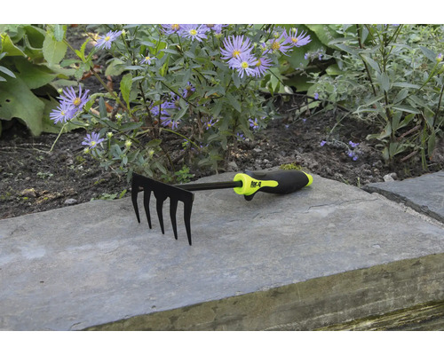 Gartenrechen mit fünf Zinken vor Blumenbeet
