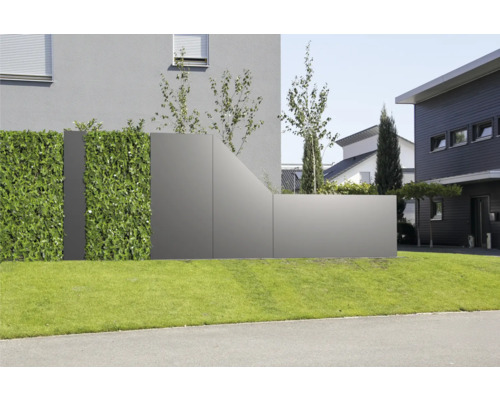 Moderner Sichtschutz aus grauen Paneelen und einer künstlichen Hecke auf einer Rasenfläche vor einem Wohnhaus.