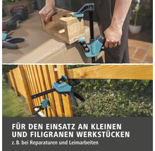 Wolfcraft Einhandzwinge im Einsatz an kleinen Werkstücken wie Holzblock und Holzzaun für Reparaturen und Leimarbeiten.