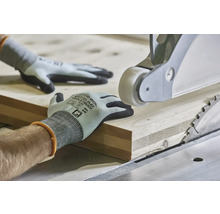 Hände in Arbeitshandschuhen führen ein Holzbrett an einer Tischkreissäge zur präzisen Holzbearbeitung.