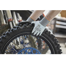 Gebol Arbeitshandschuhe Master Flex Cool und Touch beim Festhalten eines Motorradreifens mit Stollenprofil in einer Werkstatt.